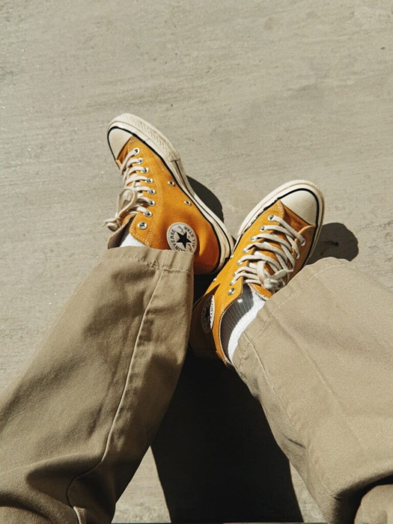 Orange converse sneakers on a person wearing tan pants.
